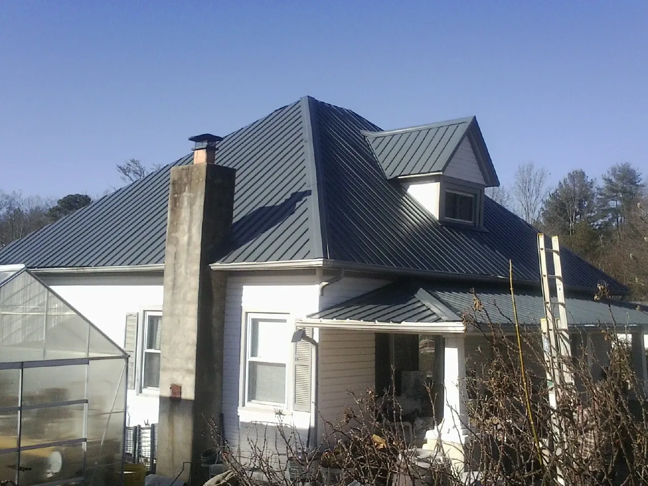 Dark blue standing seam metal roof on a white farmhouse with dormer — Slate & Tile Roof Repair by Roofing Brothers in Cherry Hill