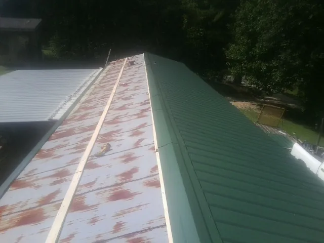 Old rusted panels beside newly installed green metal roofing — Wind Damage Roof Repair by Roofing Brothers in Cherry Hill