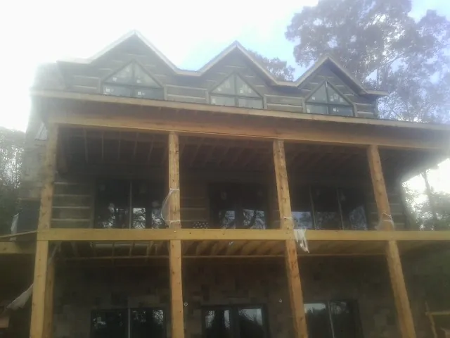 Dormers and porch framing on a large log home under construction — Roof Coating work by our crew in Cherry Hill
