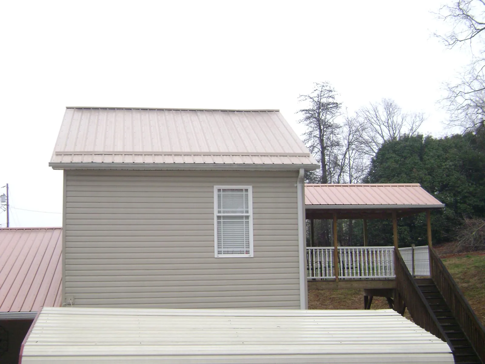 Tan metal roofs on a two story addition and attached porch, from a Roof Replacement job in Cherry Hill