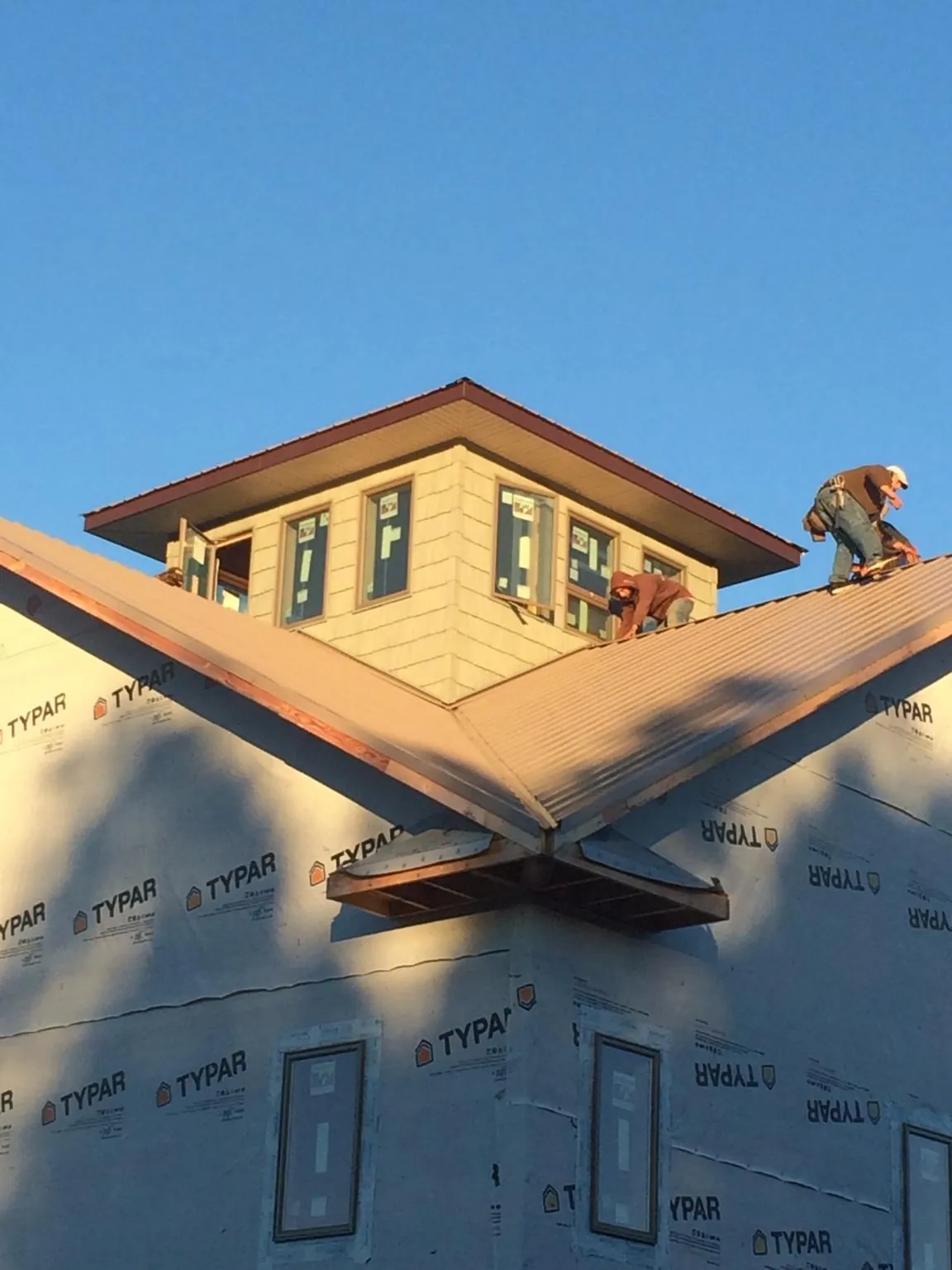 Roofers working around a rooftop cupola on a new metal roof at sunset — Roof Waterproofing in Cherry Hill by Roofing Brothers